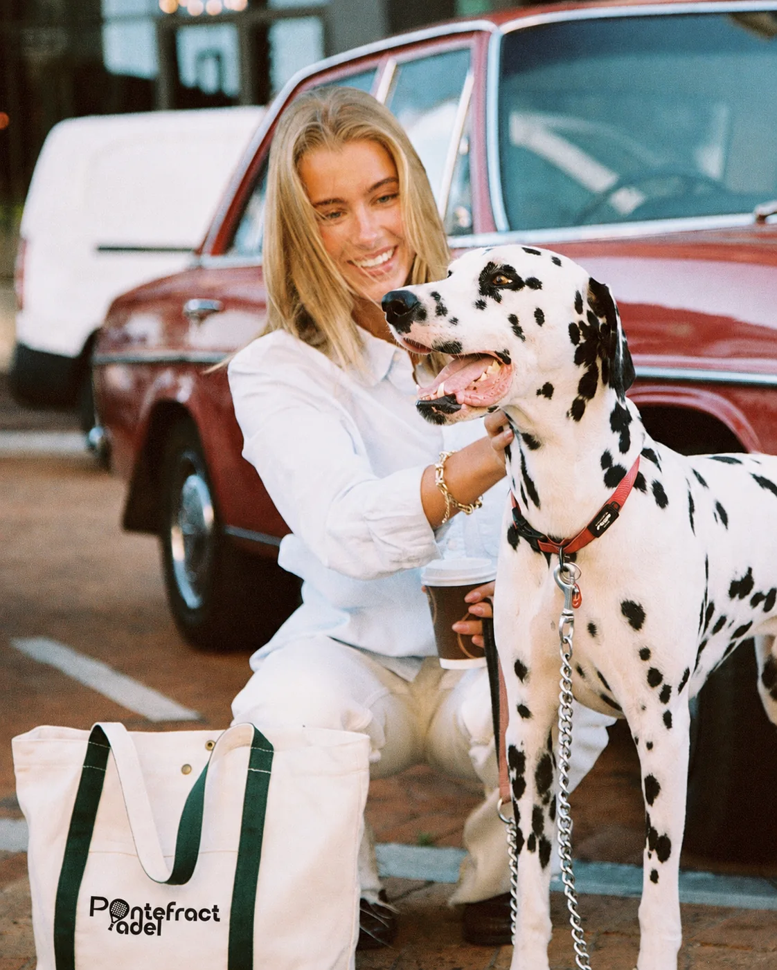 A woman with a dalmatian beside a vintage car and a Pontefract Padel tote