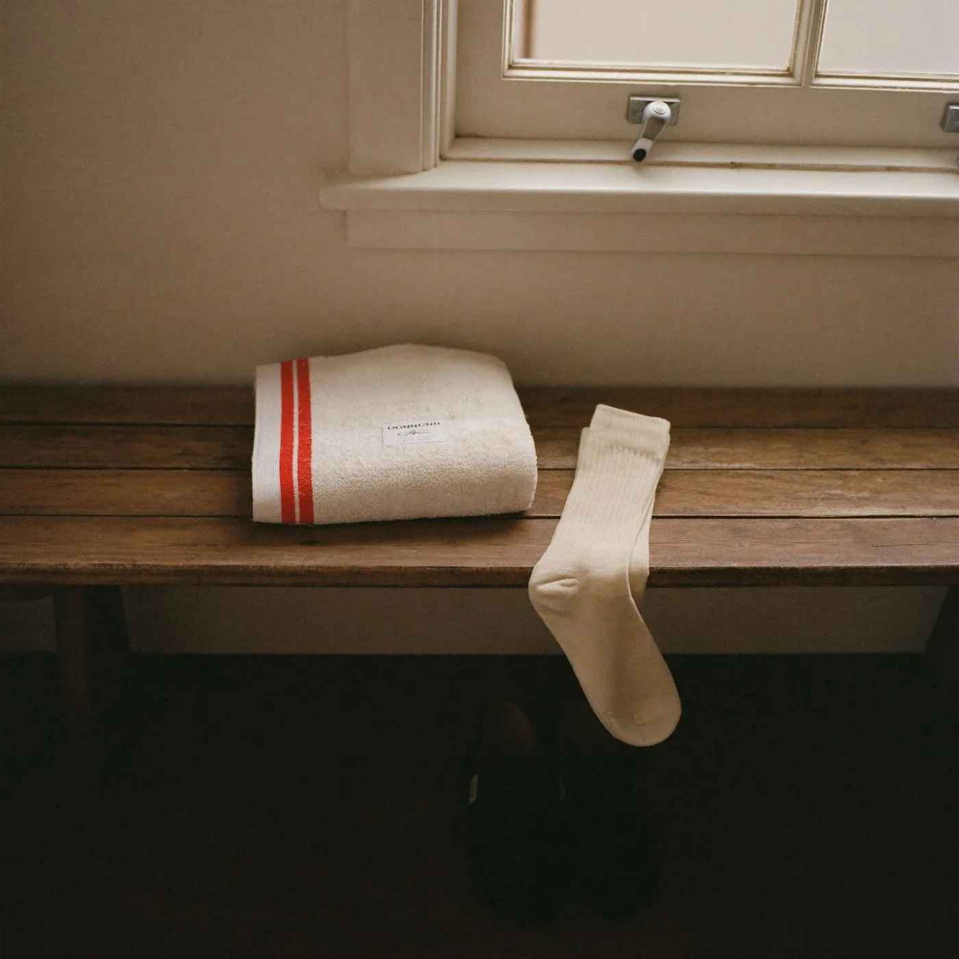 A folded striped towel and a white sock on a changing-room bench